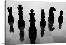 Chess pieces on chess board in black and white silhouette.