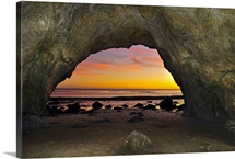 Dramatic sunset seen from inside cave on beach.