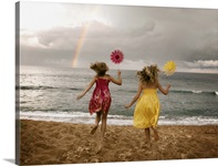 Girls running on beach holding windmills