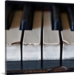 Old, antique upright piano keys displaying wear and tear.