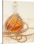 Pearl necklace draped around a perfume bottle