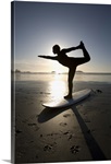 silhouette of female surfer doing bow pulling yoga pose