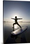 silhouette of female surfer doing warrior yoga pose