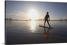 silhouette of female surfer doing yoga stretches