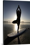 silhouette of female surfer doing yoga tree pose