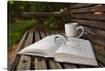 Still life of open Book, eyeglasses and coffee cup on wooden bench