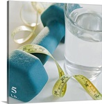 Tape measure, exercise weights and glass of water, studio shot