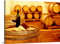 wine bottle with a wineglass and cheese on a barrel