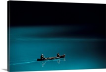 A canoe plies the mirror smooth surface of Lake Louise