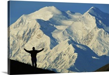 A hiker silhouetted against snow covered Mount McKinley