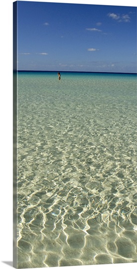 Rippled water surface of the sea with a tourist in the background, Spiaggia Dei Conigli, Italy