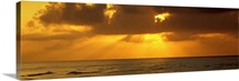 Sunbeams radiating through clouds over the ocean