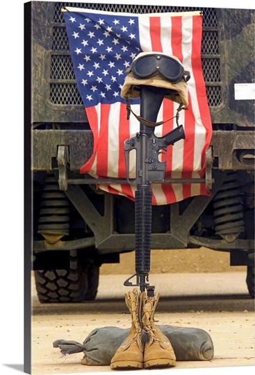 An M16A2 service rifle a pair of boots and a helmet stand in tribute to a fallen soldier