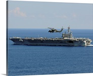 An MH 60S Seahawk helicopter flies over USS George H.W. Bush
