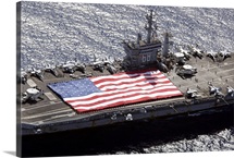 Personnel participate in a flag unfurling rehearsal on the flight deck aboard USS Nimitz