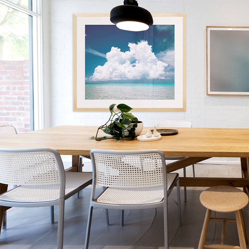 framed print of a photograph of the ocean in a bright dining room
