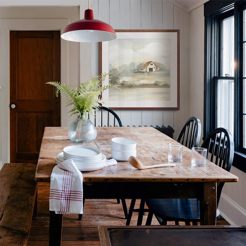 framed print of a painting of a barn hanging in a farmhouse dining room