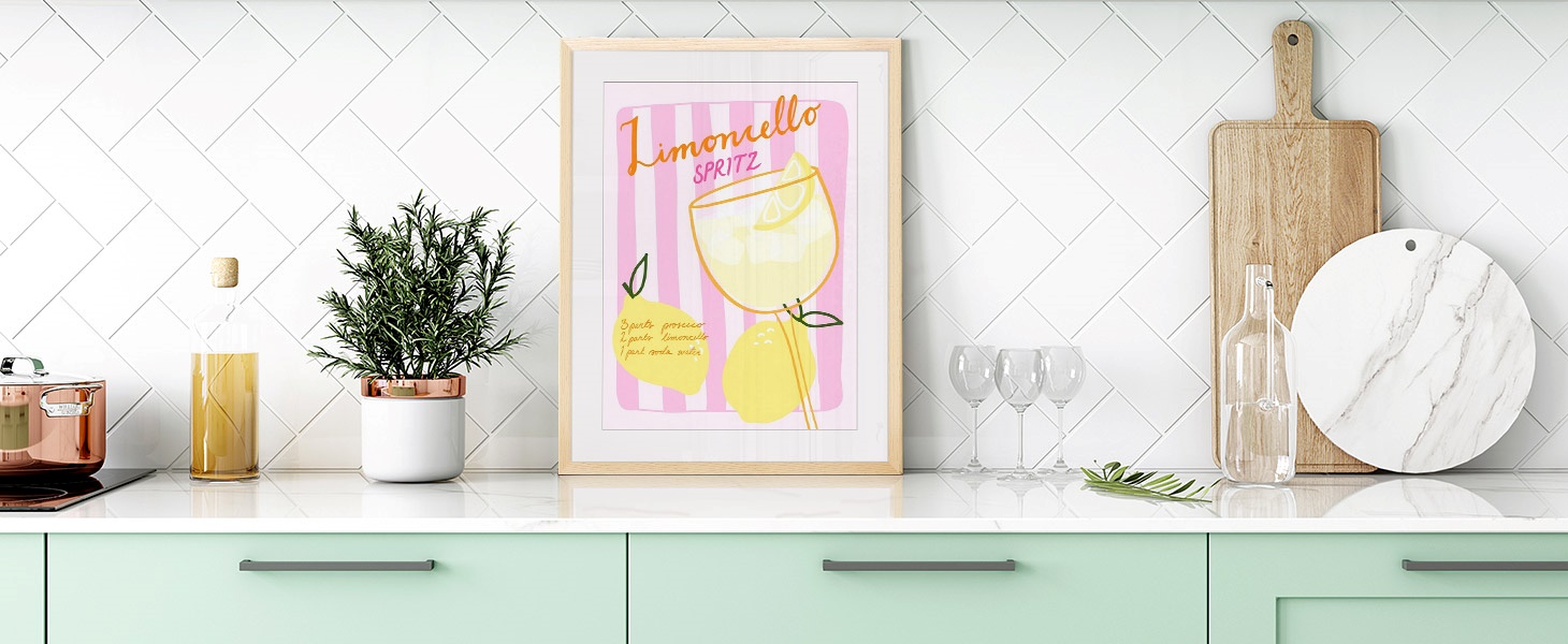 Framed print of a retro-inspired drink advertisement poster in a bright modern kitchen.