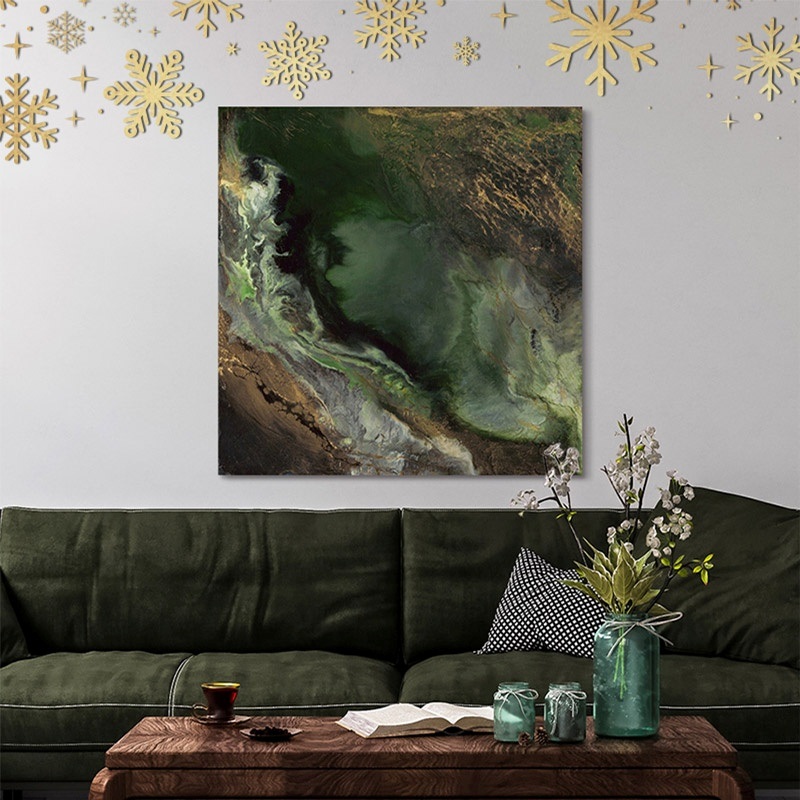 a canvas of an abstract with green hues hanging above a green sofa
