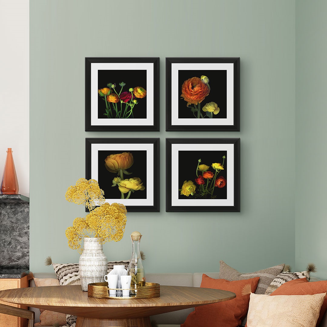 Four framed prints depicting photographs of a variety of flowers displayed above a dining room table