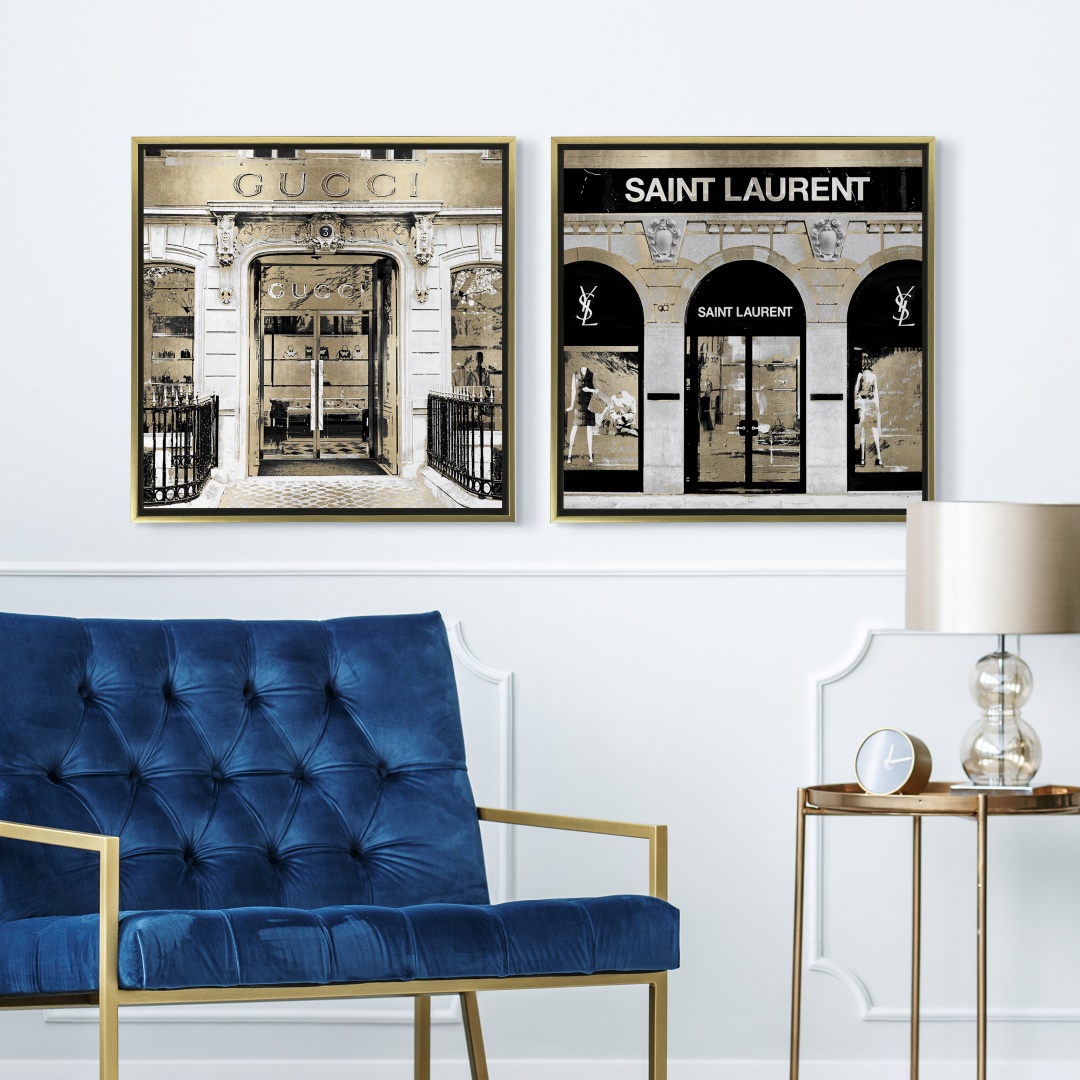 two gold, black and white canvas prints of fashion houses in gold floating frames in a glam space
