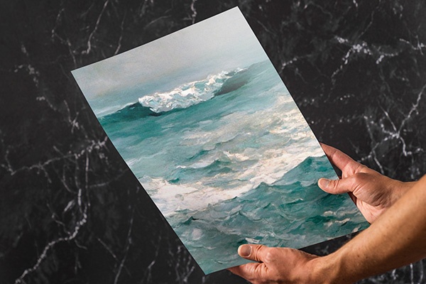 two hands holding a detailed print of ocean waves