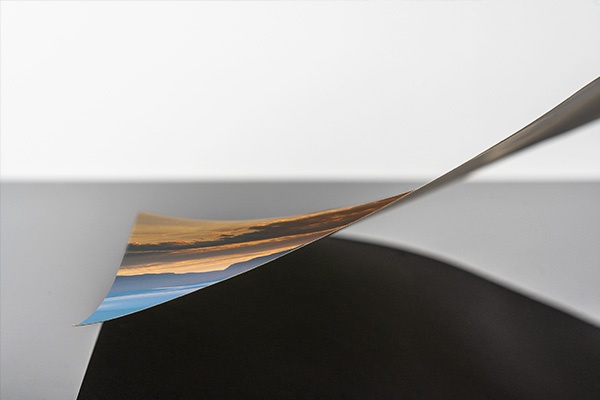 a printed art piece shown from the side being laid down onto a surface