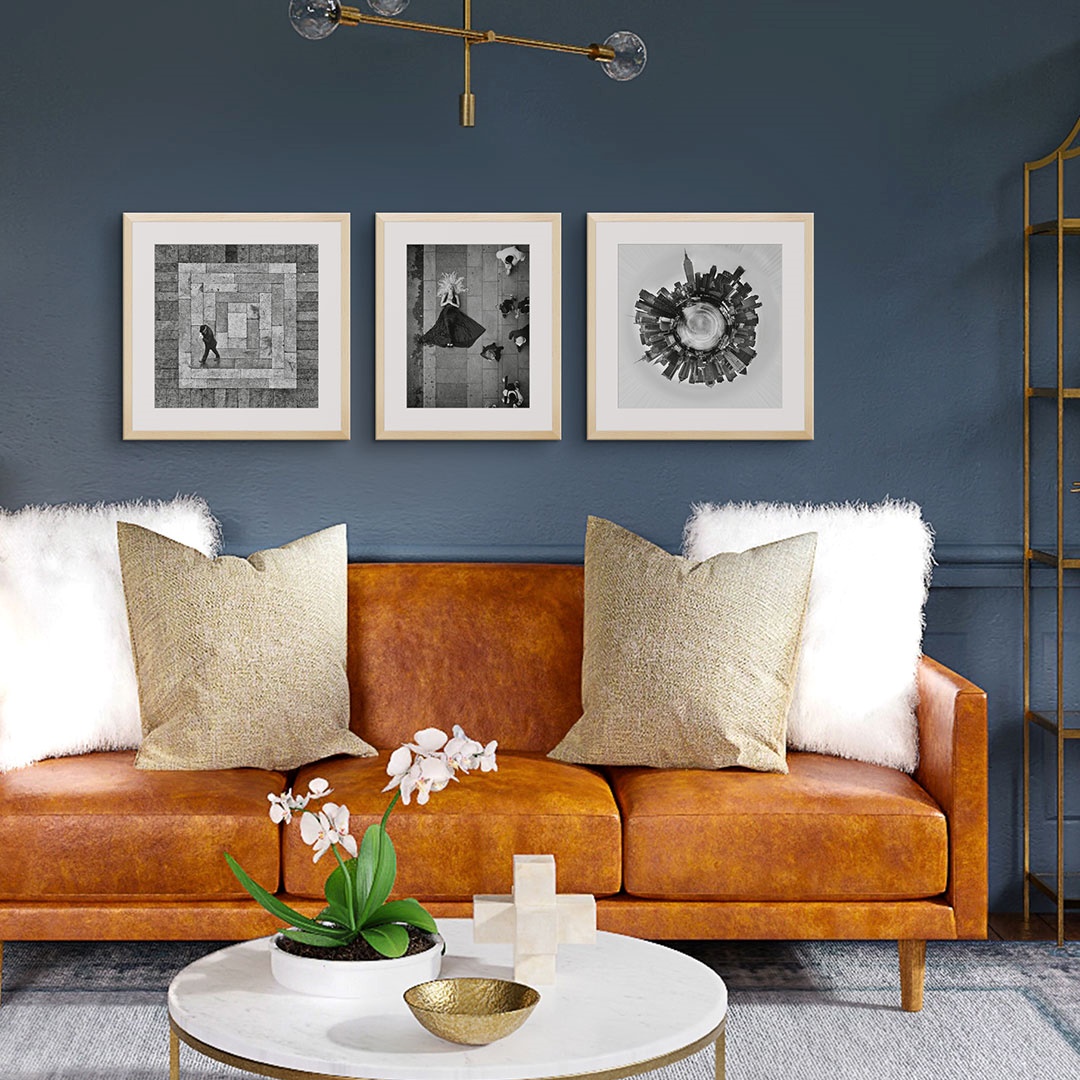 Three framed prints depicting black and white photos of a city, woman, and man over a couch