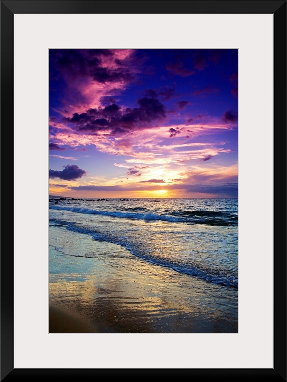 Large photograph displays the waves of the Pacific Ocean slowly coming into shore and crashing against the sandy beach of ...