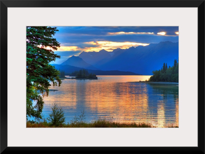 A landscape photograph of morning light reflecting on a lake in the mountains surrounded by trees.