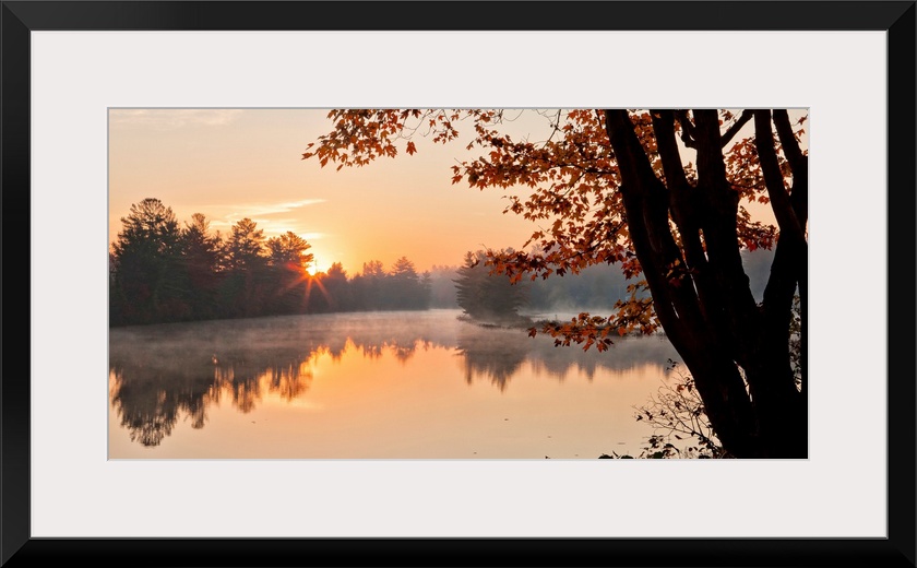 Big Canvas photo of a tranquil lake at sunrise with forests around it bathed in warm sunlight.