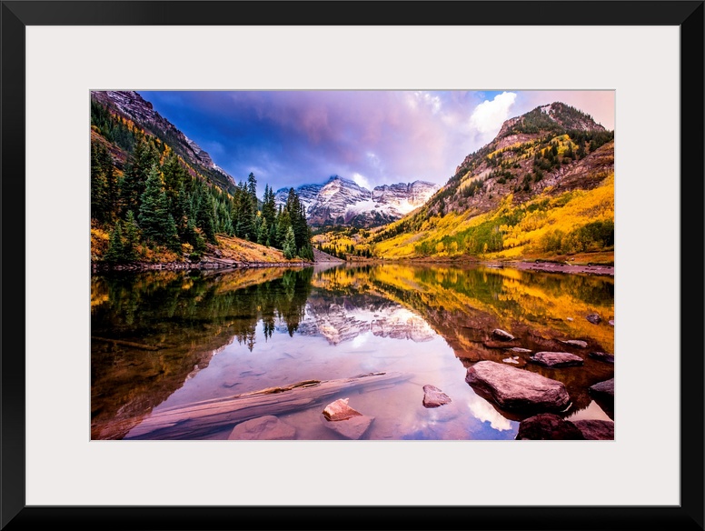 There is a warm hue to this photograph of mountainous terrain and thick foliage that reflect in still water below.