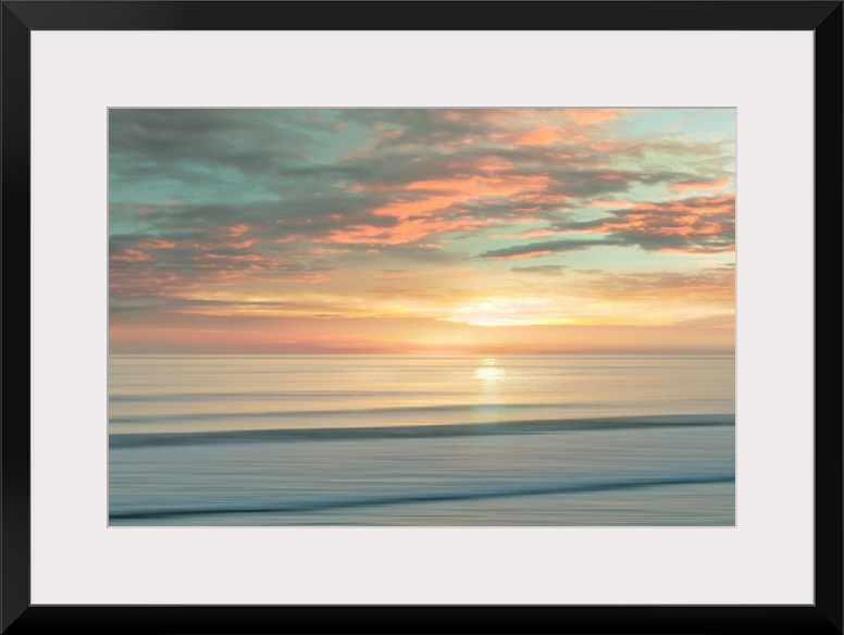 A peaceful scene of the sun slowly rising over a calm stretch of ocean. The sky glows in shades of apricot and light teal....