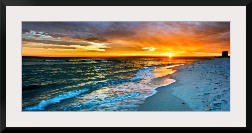 A dark beach before a panoramic orange sunset with a burning red sky. Landscape taken on Navarre Beach, Florida.