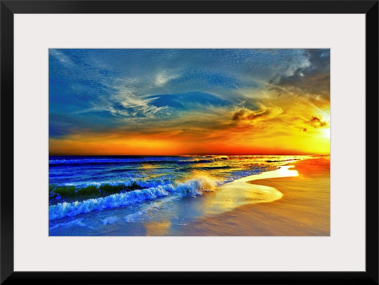 A sandy beach before a bright burning red sunset.  Waves crash onto the sandy sea shore. Landscape taken on Navarre Beach,...