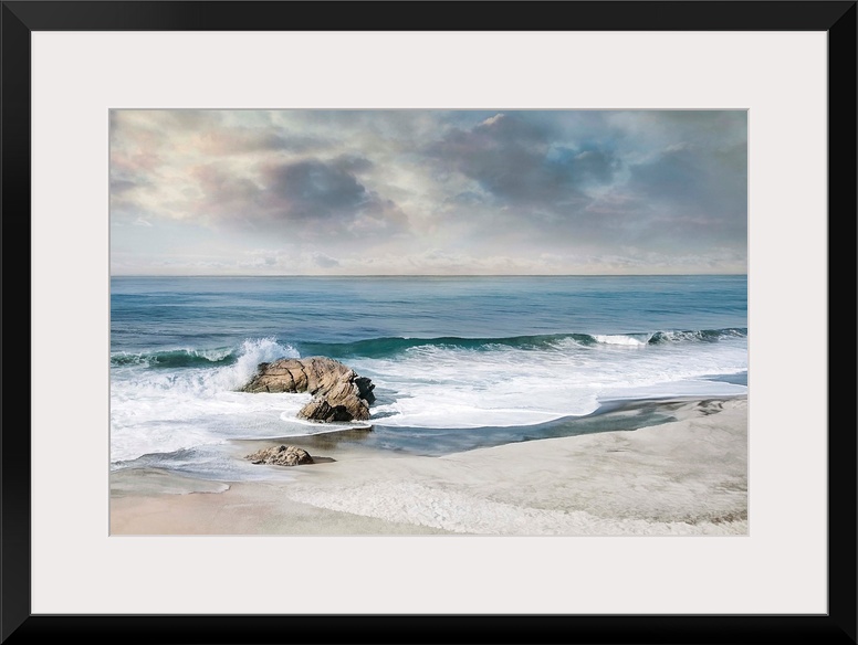 Landscape photograph of waves crashing onto a rock on the sandy shore.