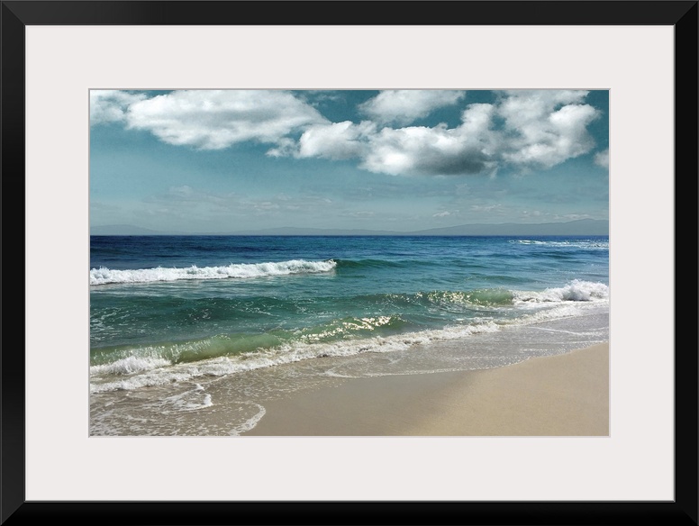 This serene photo shows rippling waves as they approach the beach with puffy white clouds in the background.