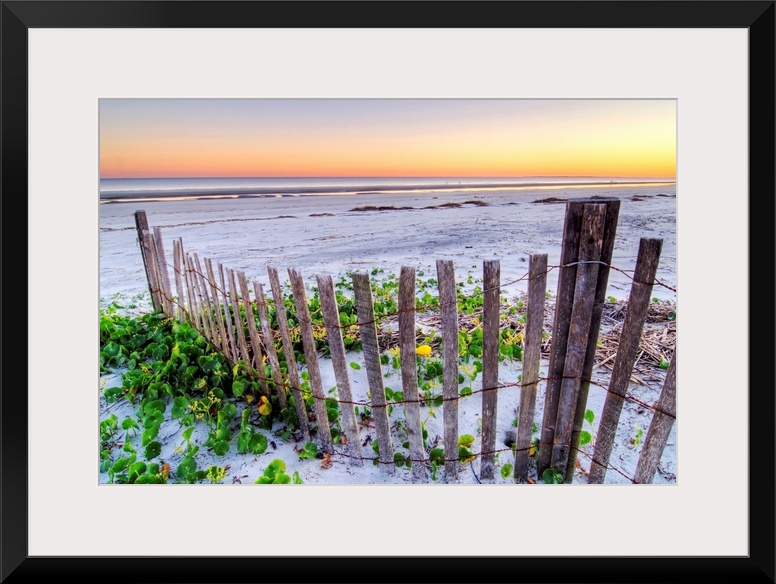 Wall art for the home or office this landscape photograph is of a battered barrier fence ends on the edge of the sandy sho...