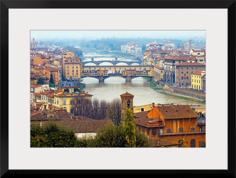 Giant photograph overlooking the Fiume Arno surrounded by a busy city within Italy.  On the shores of the river, the build...