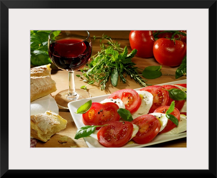 This photograph is a still life of traditional Italian food. A wood table is covered with crusty bread, red wine, tomatoes...