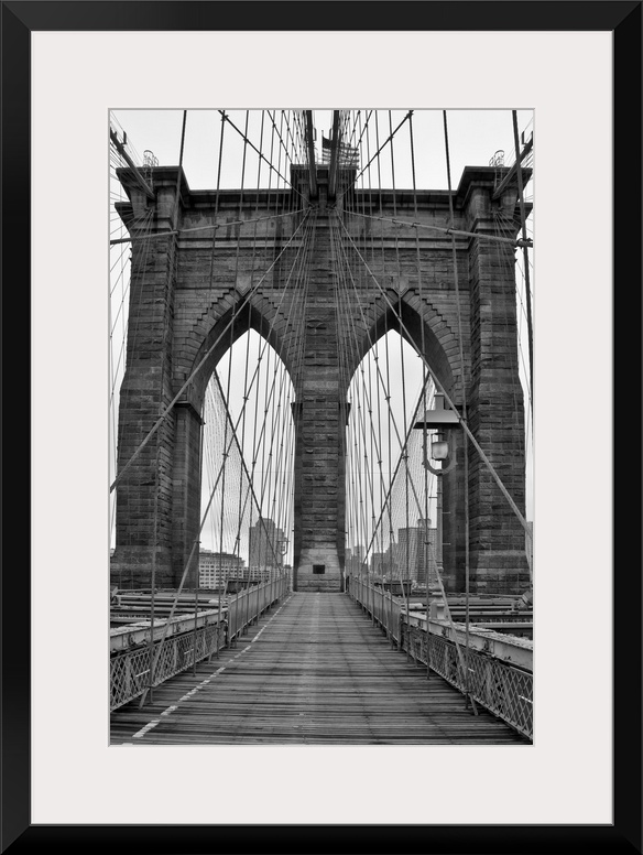 Large, vertical black and white photograph of one of the stone piers surrounded by many cables on the Brooklyn Bridge in N...