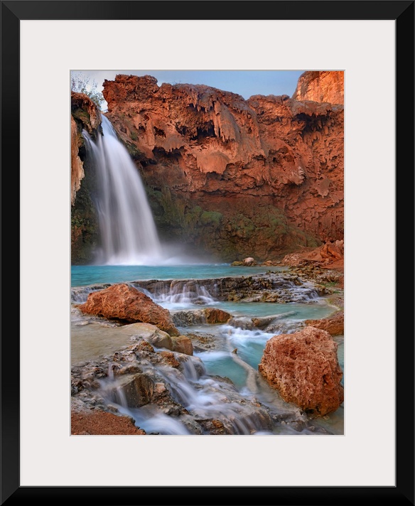Large photograph showcases water falling down a jagged cliff and splashing into the pool below before moving on down a roc...