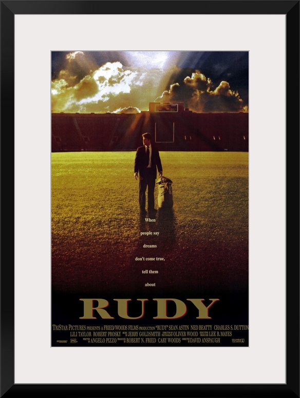 This large vertical piece is a movie poster for "Rudy". It pictures the star character walking across the football field i...