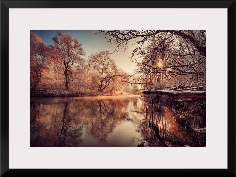 In this landscape photograph morning light reflects off a river in a forest covered with the first frost.