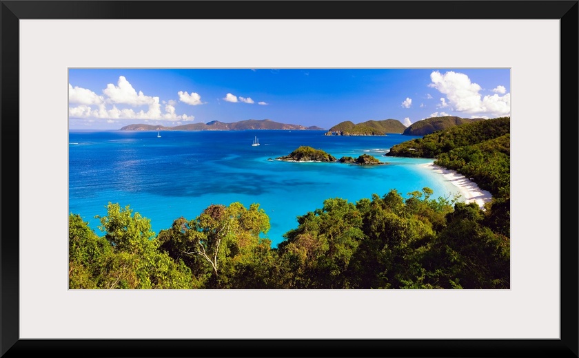 Panoramic photograph of cove with water on left and tree lined beach on right.  There are vegetation covered mountains in ...