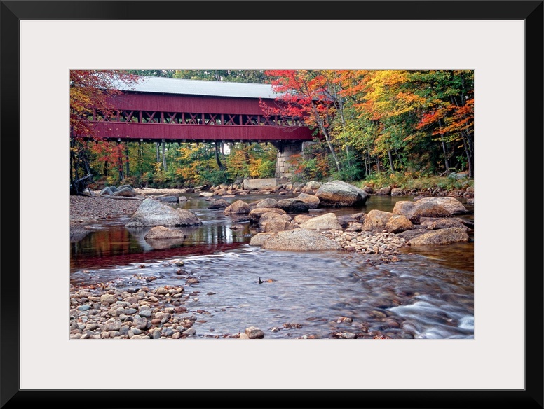 Photograph of the wooden Swift River Bridge located in Conway, New Hampshire that overlooks a river flowing through rocks ...
