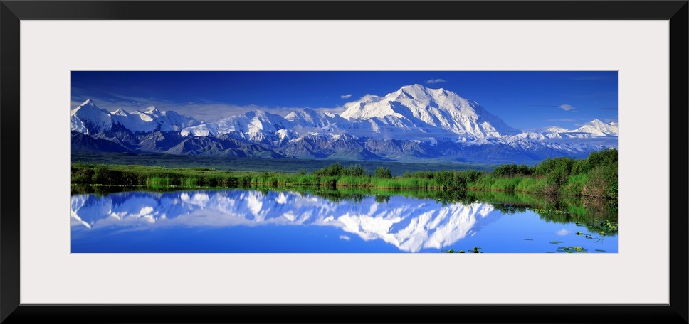 Panoramic view of snowcapped mountains and Mt. McKinley reflecting in still waters.