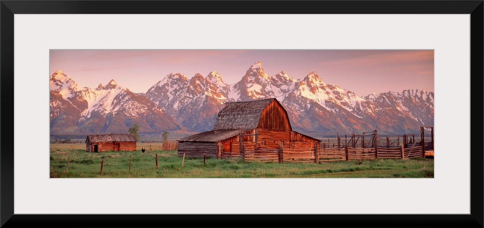 Panoramic photograph of a large barn on a farm in Grand Teton National Park in Wyoming. Located in the background are snow...