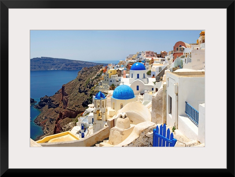 This hillside city with its famous colored roof tops overlooks a rocky Grecian sea in this panoramic photograph.