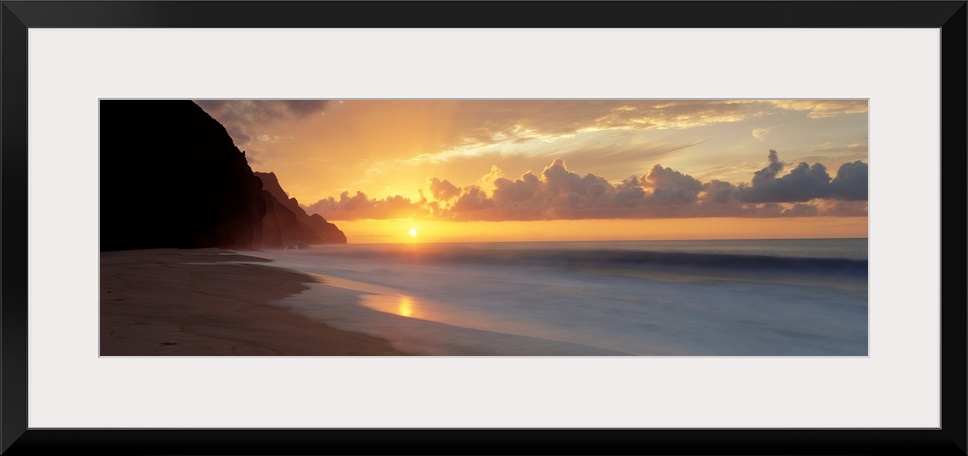 The sun sinks below the horizon viewed from the beach on a tropical Pacific island.